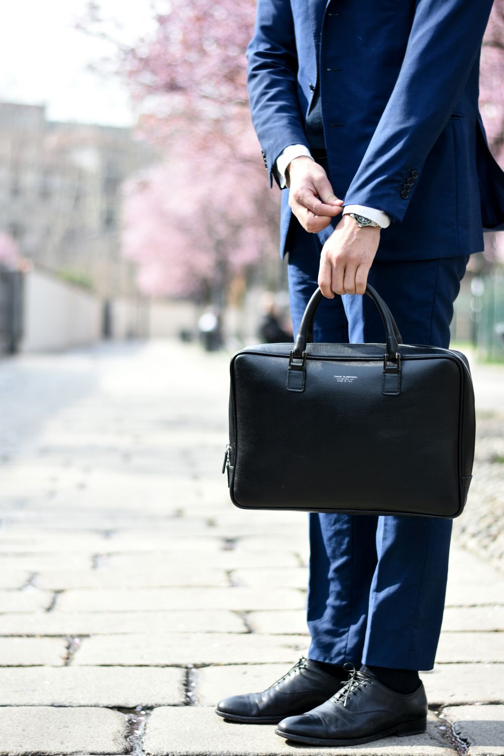 business owner in suit holding briefcase and fastening cuff link